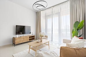 A modern living room with a flat-screen TV, wooden console, and a large plant. - Silkhaus in Julphar Cozy 1bdr In Reem Island (Abu Dhabi)