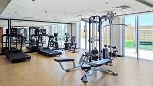 A gym with various exercise equipment, large windows, and a wooden floor. - Silkhaus in Julphar Cozy 1bdr In Reem Island (Abu Dhabi)