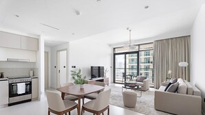 Eine moderne Wohnung mit Küche, Essbereich und Wohnzimmer. Sie verfügt über ein großes Fenster, eine Couch und einen Fernseher.