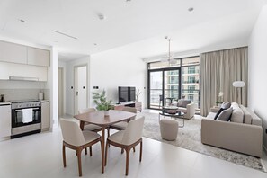 Eine moderne Wohnung mit Küche, Essbereich und Wohnzimmer. Sie verfügt über ein großes Fenster, eine Couch und einen Fernseher.