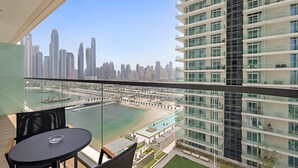 Ein Balkon mit freiem Blick auf ein modernes Hochhaus, einen Strand und eine Marina.