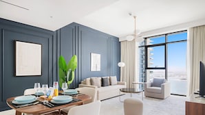 A modern living room with a dining area, a sofa, a coffee table, and a TV. - Silkhaus in Marina Vista Stunning 1bdr Sea View (Dubai)