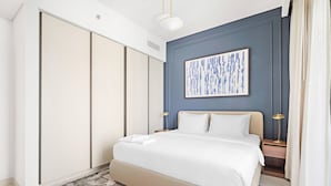 A modern bedroom with a large bed, a nightstand with a lamp, and a wardrobe. - Silkhaus in Marina Vista Stunning 1bdr Sea View (Dubai)