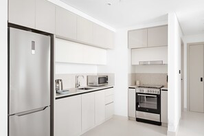 A modern kitchen with white cabinets, stainless steel appliances, and a built-in oven. - Silkhaus Stylish 1bdr Harbor View Marina Vista (Dubai)