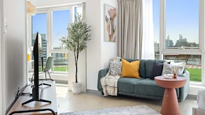 A modern living room with a sofa, a coffee table, a TV, and a potted plant. - Silkhaus Cozy Studio Madison Barsha Heights (Dubai)