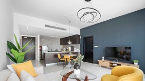 A modern living room with a glass coffee table, a yellow armchair, and a TV. - Silkhaus Horizon Tower High Floor by Al Fay Park (Abu Dhabi)