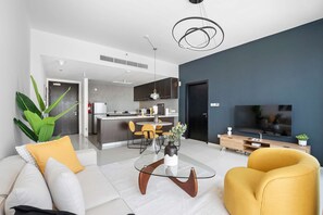 Ein modernes Wohnzimmer mit einem Glastisch, einem gelben Sessel und einem Fernseher.