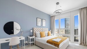 A modern bedroom with a large bed, a desk, a chair, and a view of the city through large windows. - Silkhaus Horizon Tower High Floor by Al Fay Park (Abu Dhabi)