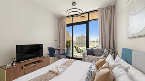 A modern hotel room with a large bed, a TV, a desk, and a view of the cityscape. - Silkhaus Cozy Studio in Al Maryah Island (Abu Dhabi)