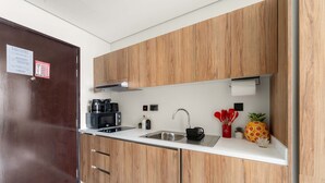 A modern kitchen with wooden cabinets, a stainless steel sink, and a coffee machine. - Silkhaus Cozy Studio in Al Maryah Island (Abu Dhabi)