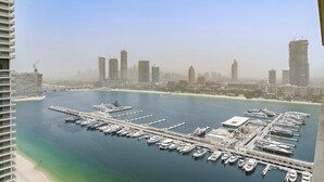 A marina with numerous boats docked, a pier extending into the water, and a city skyline in the background. - Silkhaus Emaar Beachfront Tower w Balcony (Dubai)