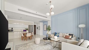 A modern living room with a sofa, coffee table, and dining area. - Silkhaus Emaar Beachfront Tower w Balcony (Dubai)