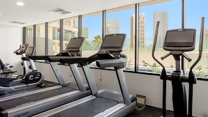 A gym with treadmills and an elliptical machine, large windows with a city view, and a ceiling with recessed lighting. - Silkhaus Elegant 1bdr Retreat Al Maryah Island (Abu Dhabi)