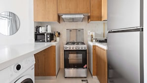 Une cuisine compacte dotée de meubles en bois, d’une cuisinière en acier inoxydable, d’un four à micro-ondes et d’un four encastré.
