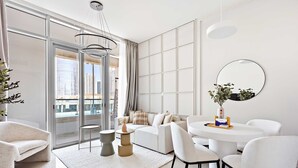 Un salon moderne avec un canapé, des fauteuils, une table basse et une grande fenêtre donnant sur la ville.