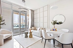 A modern living room with a sofa, chairs, a coffee table, and a large window with a city view. - Silkhaus New 1bdr Julphar Tower In Reem Island (Abu Dhabi)