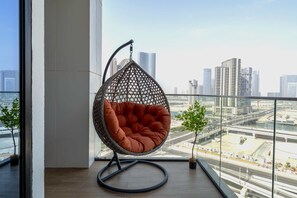 A hanging chair with a cushioned seat in a modern room with large windows overlooking a cityscape. - Silkhaus Elite 1bdr Stay in Al Maryah Island (Abu Dhabi)