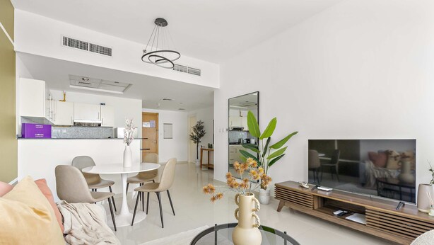 A modern living room with a glass coffee table, a sofa, a TV, and a dining area with chairs and a table. - Silkhaus Bayside 1bdr Stay Marina Bay Tower (Abu Dhabi)