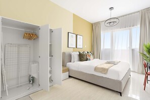 A bedroom with a bed, a walk-in closet, a radiator, and a window with curtains. - Silkhaus Bayside 1bdr Stay Marina Bay Tower (Abu Dhabi)