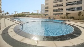 A swimming pool with a circular design, surrounded by a tiled deck. - Silkhaus Bayside 1bdr Stay Marina Bay Tower (Abu Dhabi)