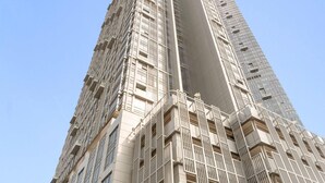 A tall, modern building with a unique architectural design, featuring a prominent vertical element and multiple balconies. - Silkhaus 1bdr in Horizon Tower Al Fay Park Near (Abu Dhabi)
