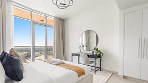 A modern bedroom with a large bed, a desk, and a view of the city. - Silkhaus Spacious 2bdr Stay in Julphar Tower (Abu Dhabi)