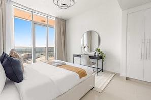 Ein modernes Schlafzimmer mit einem großen Bett, einem Schreibtisch und Blick auf die Stadt.