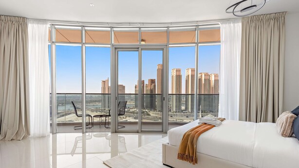 A modern bedroom with a large window, a white bed, and a view of a cityscape. - Silkhaus Spacious 2bdr Stay in Julphar Tower (Abu Dhabi)
