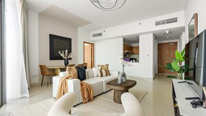 A modern living room with a sofa, coffee table, and a dining area with chairs. - Silkhaus Spacious 2bdr Stay in Julphar Tower (Abu Dhabi)
