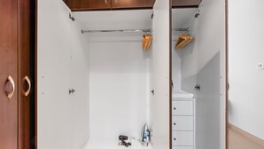 Um closet espaçoso com interior branco, armários de madeira e um cabideiro.