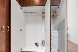 A walk-in closet with a white interior, wooden cabinets, and a hanging rack. - Silkhaus in Yasmine Near Golf Course Club (Abu Dhabi)