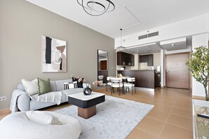 A modern living room with a sofa, coffee table, and dining area. - Silkhaus in Yasmine Near Golf Course Club (Abu Dhabi)