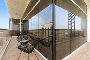 A balcony with glass walls, black chairs, and a tiled floor. - Silkhaus in Yasmine Near Golf Course Club (Abu Dhabi)