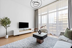 A modern living room with a flat-screen TV, a minimalist coffee table, a potted plant, and a sofa. - Silkhaus in Yasmine Near Golf Course Club (Abu Dhabi)
