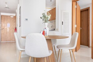 Un espace repas moderne avec une table ronde en bois, deux chaises blanches et un vase rempli de fleurs.
