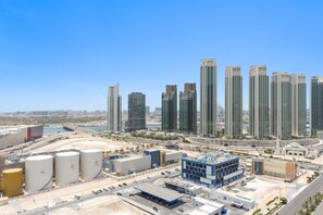 Un quartier urbain dense, avec de grands immeubles modernes, un parking et un vaste complexe industriel.