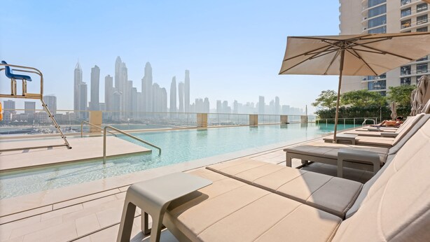 A rooftop pool with lounge chairs and an umbrella, overlooking a city skyline. - Silkhaus 1bdr w Beach Access Marina Vista (Dubai)