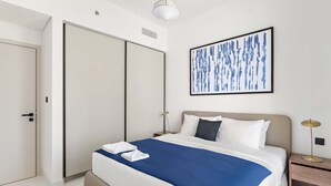 A modern hotel room with a large bed, a wardrobe, a bedside table with a lamp, and a wall art piece. - Silkhaus 1bdr w Beach Access Marina Vista (Dubai)
