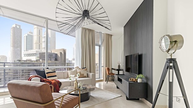 A modern living room with a large window, a sofa, a coffee table, and a TV. - Silkhaus Luxury Studio Sky Gardens Difc Views (Dubai)