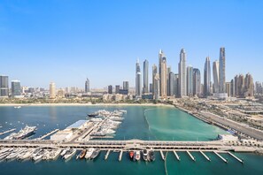 A marina with numerous boats docked, a large building complex in the background, and a clear blue sky. - Silkhaus Family Friendly 2bdr Private Beach (Dubai)