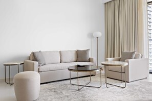 A modern living room with a sofa, two side tables, and a floor lamp. - Silkhaus Harbor View Marina Vista Private Beach (Dubai)