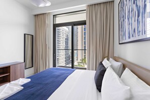 A hotel room with a bed, a desk, a window with curtains, and a city view. - Silkhaus Harbor View Marina Vista Private Beach (Dubai)