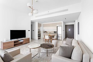 A modern living room with a flat-screen TV, sofa, coffee table, and dining area. - Silkhaus Harbor View Marina Vista Private Beach (Dubai)