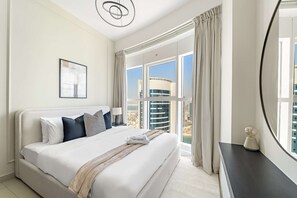 A modern hotel room with a large bed, a view of a cityscape, and a large window with curtains. - Silkhaus Elite 2bdr at Sigma I in Al Reem Island (Abu Dhabi)