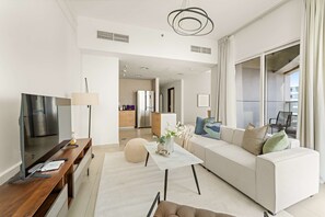 A modern living room with a sofa, coffee table, and TV. There is a kitchen in the background. - Silkhaus Elite 2bdr at Sigma I in Al Reem Island (Abu Dhabi)