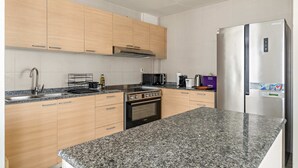 A modern kitchen with granite countertops, stainless steel appliances, and wooden cabinets. - Silkhaus Elite 2bdr at Sigma I in Al Reem Island (Abu Dhabi)