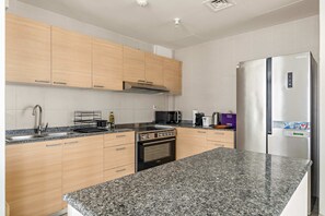A modern kitchen with granite countertops, stainless steel appliances, and wooden cabinets. - Silkhaus Elite 2bdr at Sigma I in Al Reem Island (Abu Dhabi)