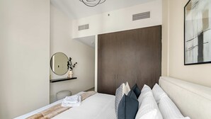 A modern hotel room with a large bed, a wardrobe, a mirror, and a framed artwork on the wall. - Silkhaus Elite 2bdr at Sigma I in Al Reem Island (Abu Dhabi)