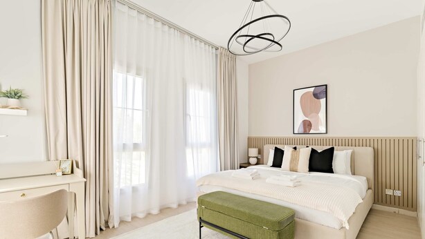 Quarto moderno com cama, mesa de cabeceira, abajur e escrivaninha com cadeira.
