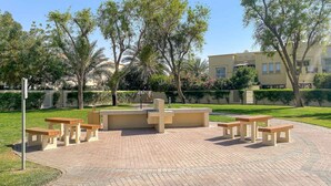 Uma área externa pavimentada com bancos e um jardim central.